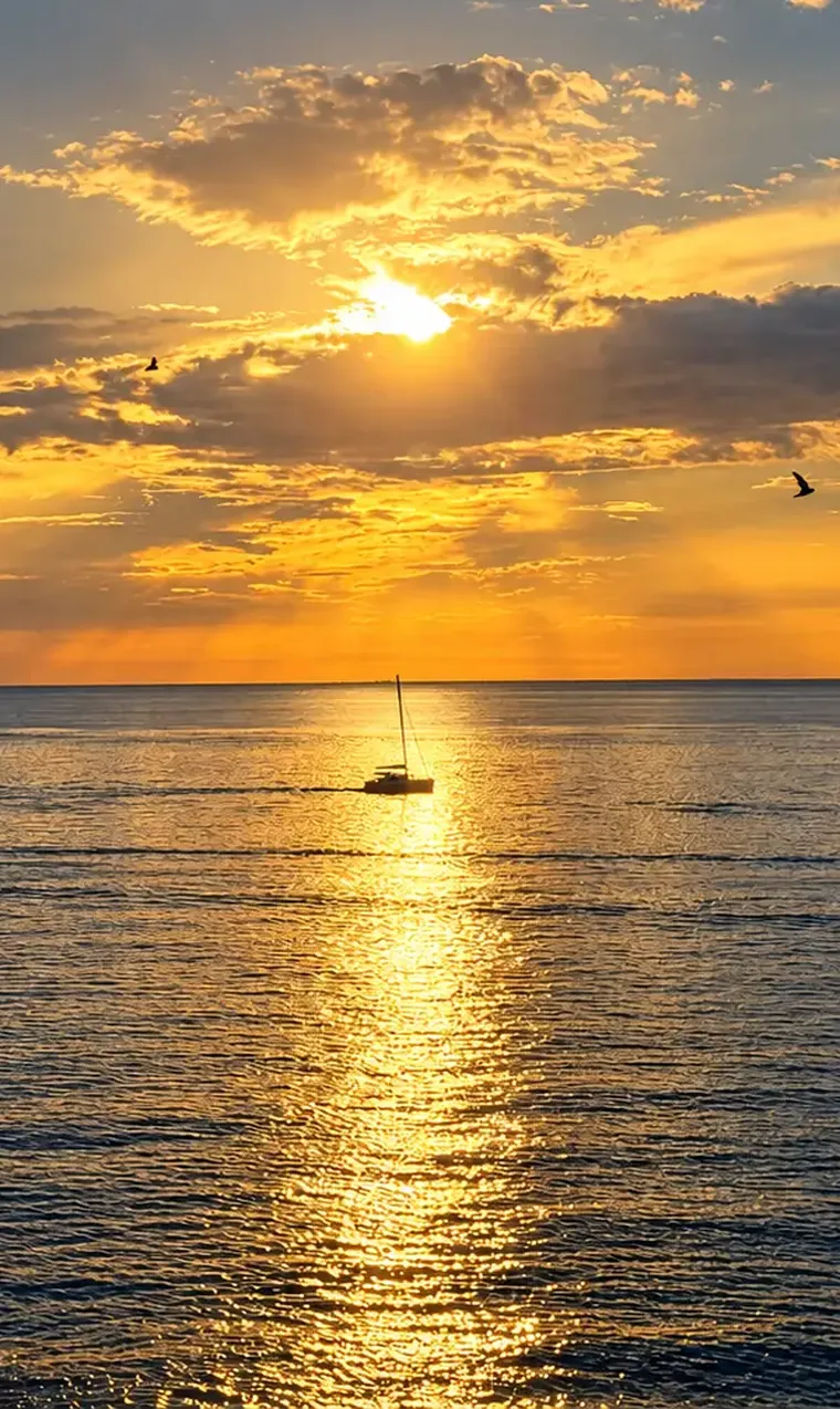 A sailboat silhouetted on the Caribbean Sea as the sun sets over Cozumel